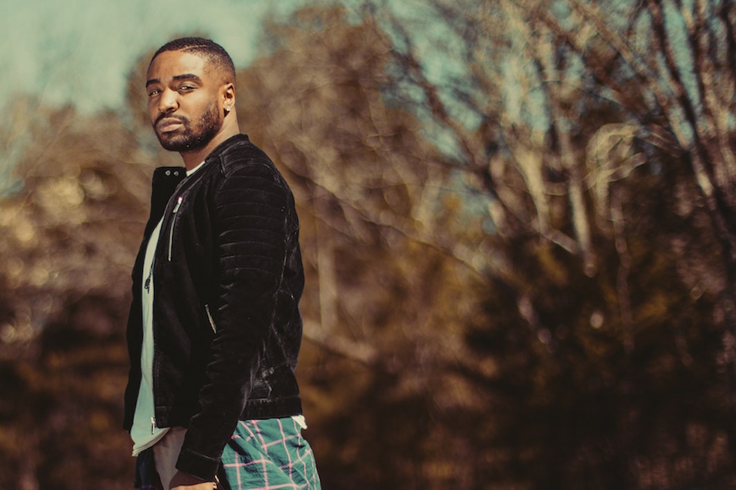 A man in black leather jacket standing outside
